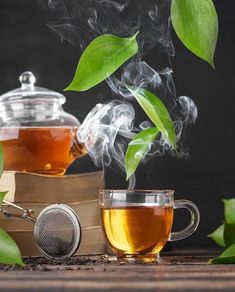 a tea pot with steam rising out of it next to a glass cup filled with green tea