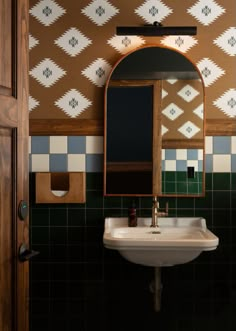 a bathroom sink sitting under a mirror next to a wooden door