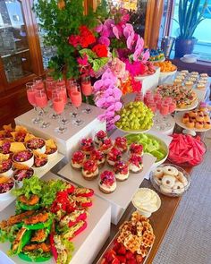 an assortment of desserts and pastries on display at a buffet table with flowers in the background