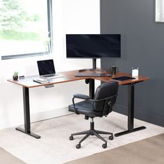 an office desk with two monitors and a laptop on it in front of a window