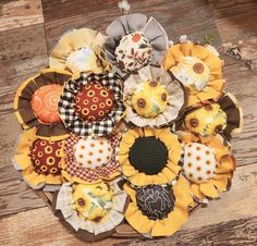 an arrangement of sunflowers are arranged on a wooden table with fabric flowers in the center