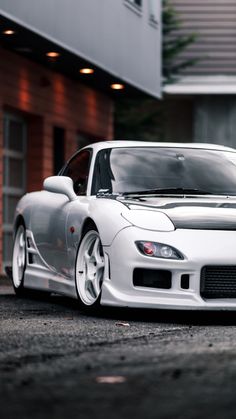 a white sports car parked in front of a building