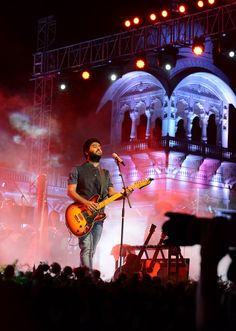 a man standing on top of a stage holding a guitar