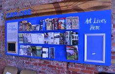 there is a blue sign that says art lives here on the side of a brick wall