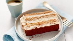 a piece of cake sitting on top of a white plate next to a cup of coffee