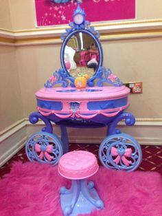 a pink and blue vanity with a mirror on it's side, next to a pink rug