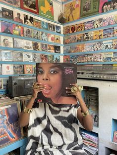 a woman sitting in front of a record store holding up a vinyl album to her face