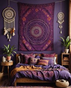 a bed with purple sheets and pillows in front of a large tapestry hanging on the wall