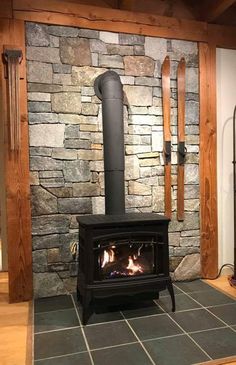 a wood burning stove in front of a stone wall