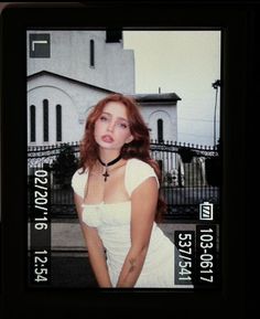 a woman with red hair is posing in front of a building