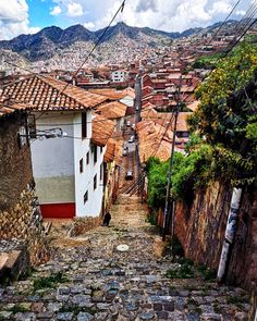 an old cobblestone street with houses and mountains in the background