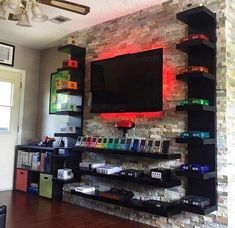 a living room with a television on the wall and shelves full of items in front of it