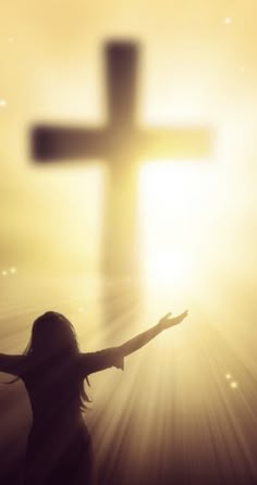 a woman with her arms outstretched in front of a cross