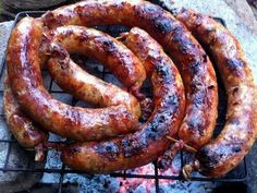 several sausages are cooking on an outdoor grill