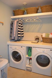 a washer and dryer in a laundry room with clothes hanging on the rack