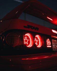 the tail light of a red sports car with stars and circles on it's hood