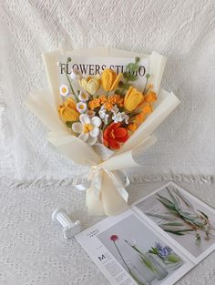 a bouquet of flowers sitting on top of a table next to an open book and magazine