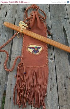 a brown bag with fringes and a wooden stick on top of it next to a fence