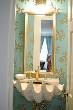 a bathroom sink sitting under a mirror in front of a wall mounted faucet