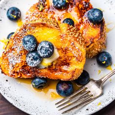 french toast with blueberries and powdered sugar on a plate next to a fork