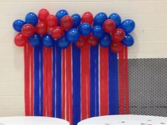 some red, white and blue balloons are hanging on the wall in front of chairs