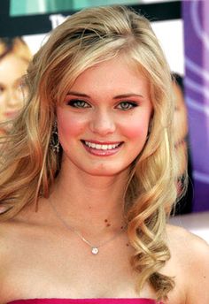 a woman in a strapless dress smiling at the camera with her hair blowing back