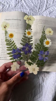 a person holding an open book with flowers on it