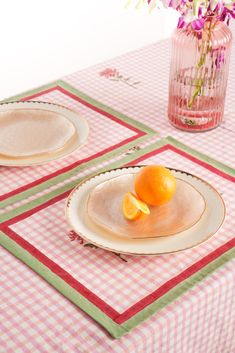 two plates with oranges on them are sitting on a pink and green tablecloth