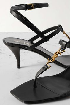 SAINT LAURENT Cassandra embellished leather sandals | NET-A-PORTER Luxury Gold T-strap Sandals, Gold Luxury Open Toe T-strap Sandals, Gold Open Toe Luxury T-strap Sandals, Luxury Gold T-strap Open Toe Sandals, Luxury Gold T-strap Sandals With Open Toe, Designer Open Toe T-strap Sandals For Evening, Luxury Black T-strap Sandals, Designer T-strap Sandals For Evening, Luxury High Heel T-strap Sandals For Evening