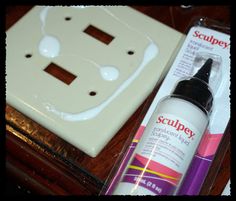 a bottle of glue sitting on top of a wooden table next to a light switch