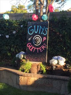 a sign that says gums is glitter in front of some flowers and bushes with pom - poms