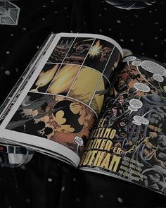 an open comic book sitting on top of a bed