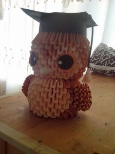 an origami graduation hat made to look like a teddy bear on a table