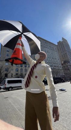 a man is holding an umbrella in the middle of a city square with tall buildings behind him