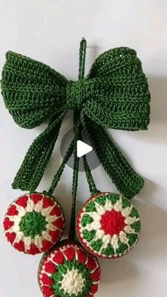 crocheted ornaments hanging from a green ribbon on a white wall with a bow