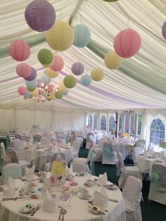 tables and chairs are set up in a tent with paper lanterns hanging from the ceiling