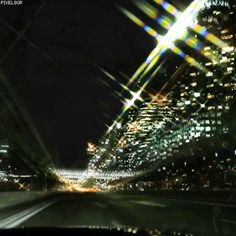 the city lights are shining brightly in the night sky from inside a moving vehicle's windshield