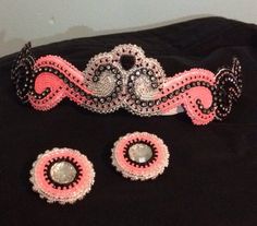 a tiara and earring set made out of beaded fabric with pink accents