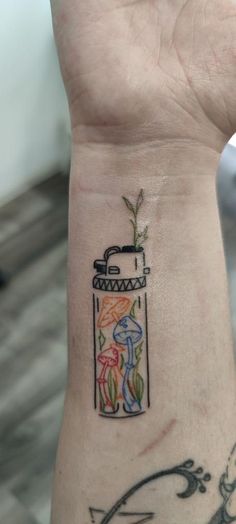 a person with a tattoo on their wrist holding up a small jar filled with flowers