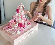 a young woman is decorating a pink and white flowered cake with flowers on it