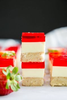 strawberry jello dessert bars stacked on top of each other with strawberries in the background