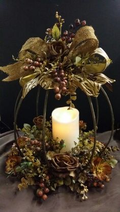 a candle is sitting on top of a table with flowers and leaves around it,