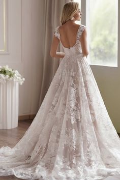 a woman in a wedding dress looking out the window with her back to the camera