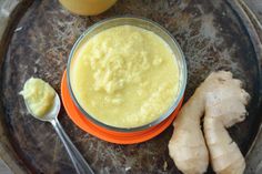 a glass bowl filled with yellow liquid next to sliced ginger