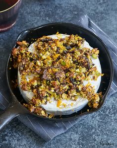 a pan filled with food sitting on top of a table next to a glass of wine