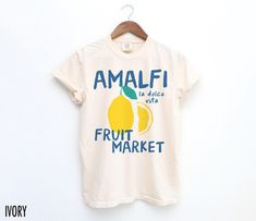 Cheers to la dolce vita with this retro-inspired Amalfi Fruit Market tee! Featuring a hand drawn graphic, this shirt captures the essence of Italian travel and timeless style. Perfect for those who dream of sunny days in Italy. We use professional quality DGT printing on all our apparel. Direct-to-garment, or DTG, is a high quality printing method that sprays ink directly onto the garment so there is no peeling or cracking. This fabulous graphic will be printed on a Comfort Colors Unisex T-Shirt Tomato Girl Summer, Lemon Shirt, Tomato Girl, Italy Shirt, Italian Travel, Italian Shirts, Fruit Shirt, Fruit Market, Food Shirt