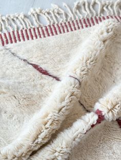 a white and red blanket laying on top of a wooden floor