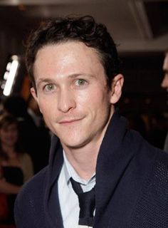 a man wearing a suit and tie standing in front of a crowd at an event