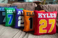 four pillows with different colors and numbers are on a couch in front of a coffee table