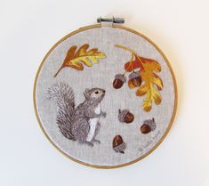 an embroidered squirrel with acorns and leaves on it's back is sitting in front of a white wall